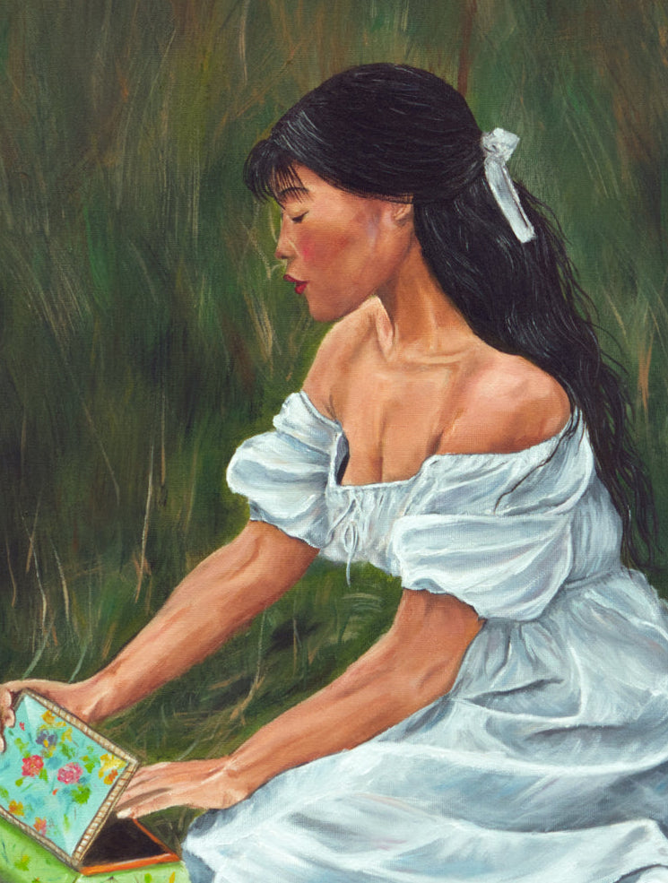 Woman in a white dress sitting in grass, opening a colorful box.